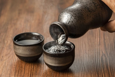 黒い徳利からお猪口へ日本酒を注ぐ様子